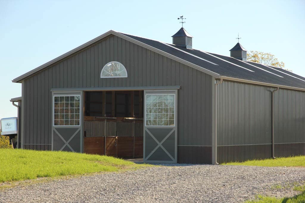 20x30 gray agricultural pole barn being used to house horses