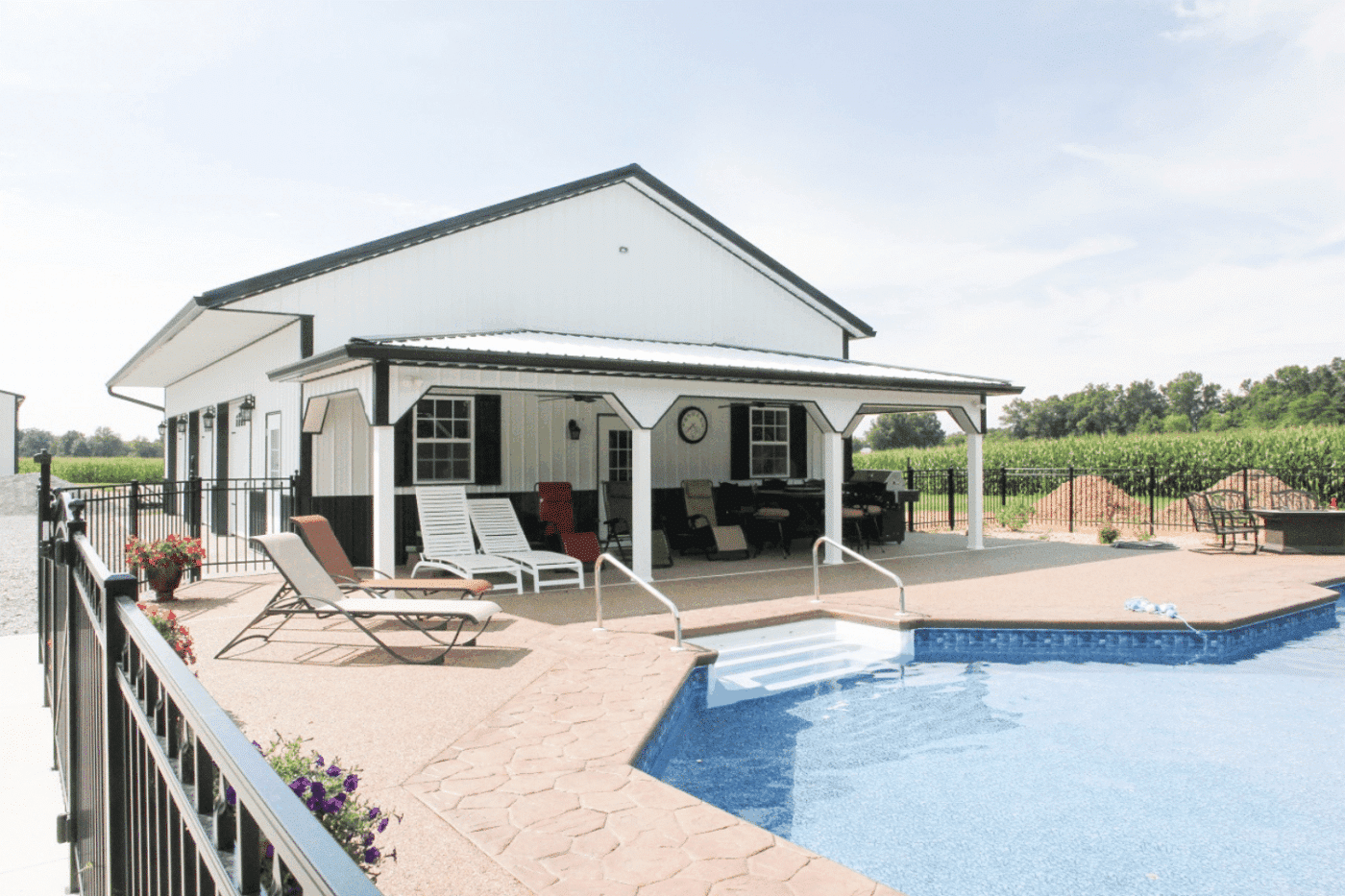 a white 24x24 barndominium standing outside by a pool