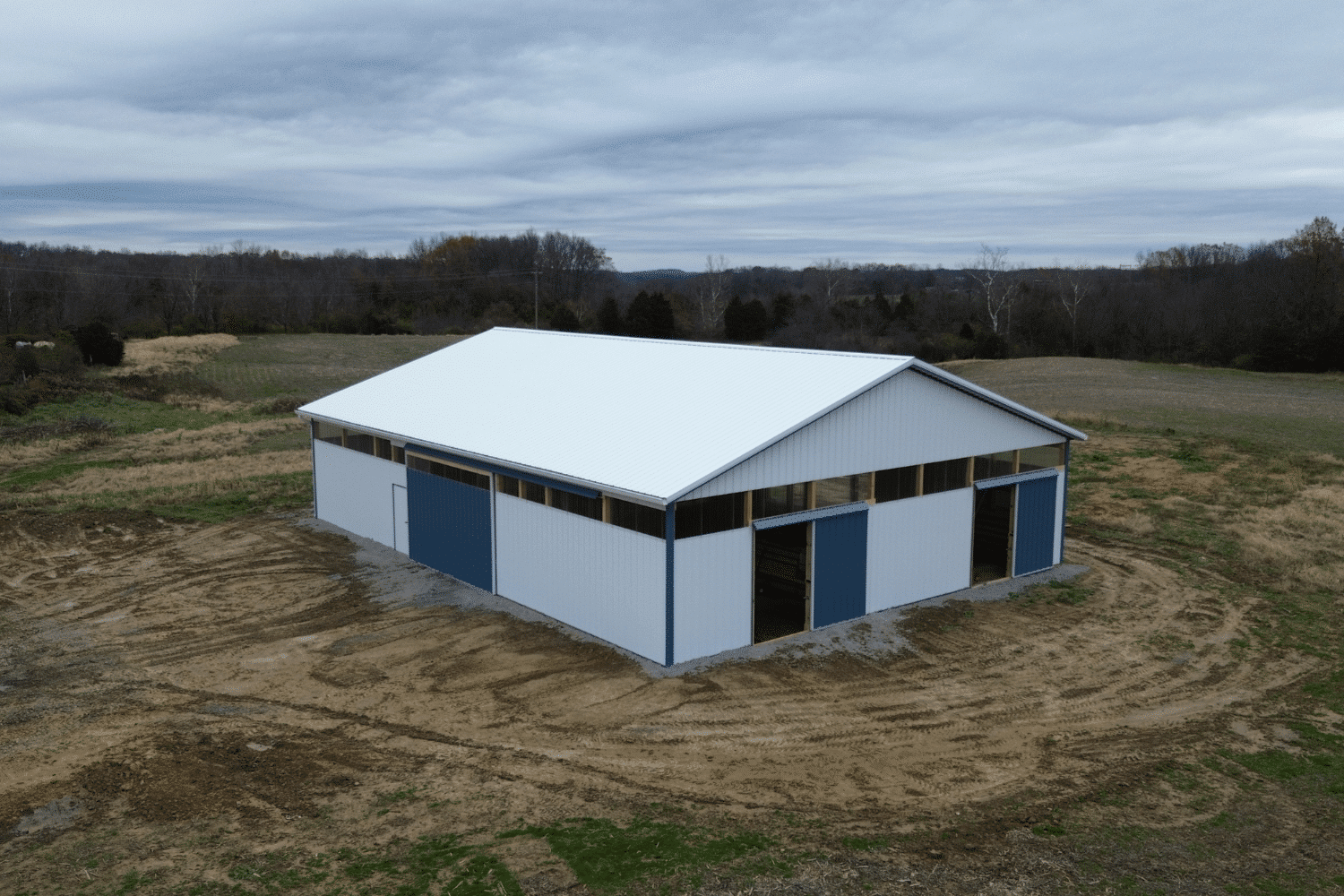 white 30x70 agricultural pole barn with blue slider doors and trim plus clear paneling along top between roof and building base