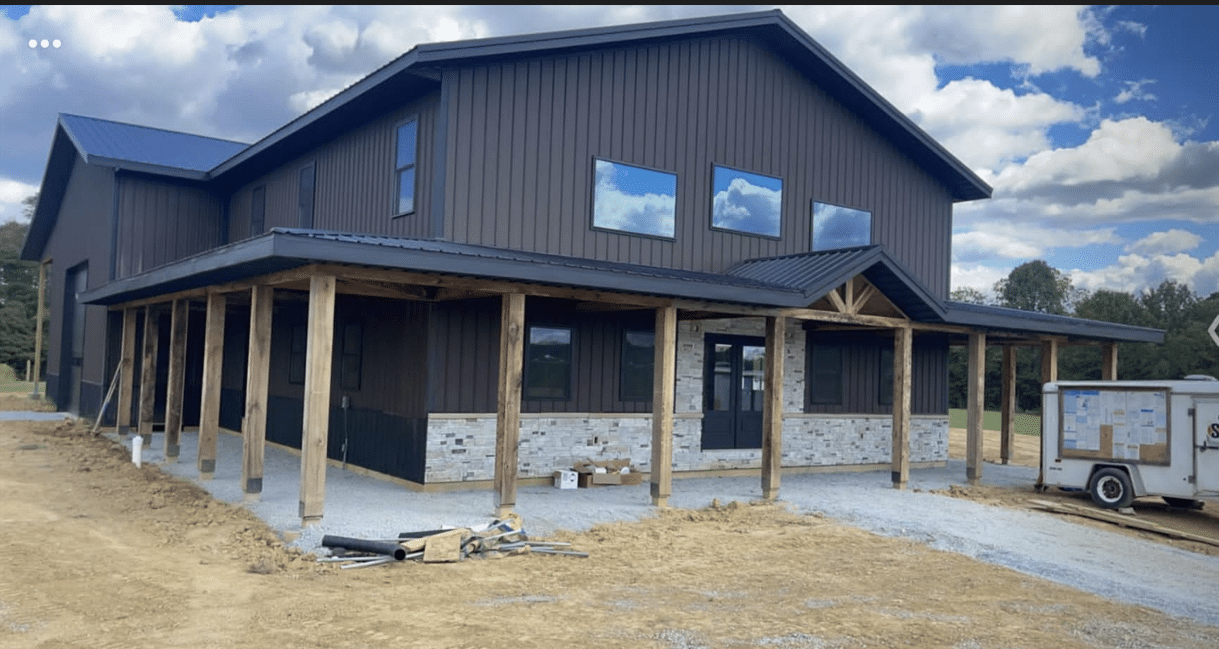 A black 80x100 commercial pole barn with a porch