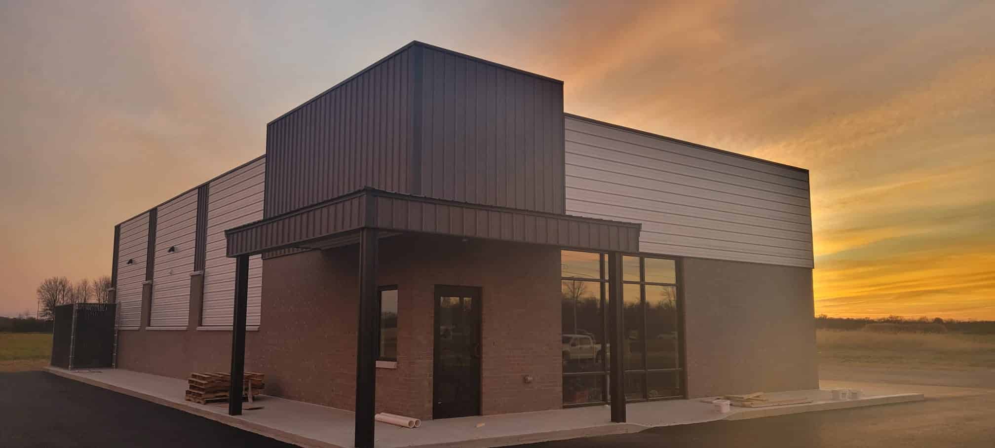 A 80x120 commercial pole barn blocking the sunset behind it