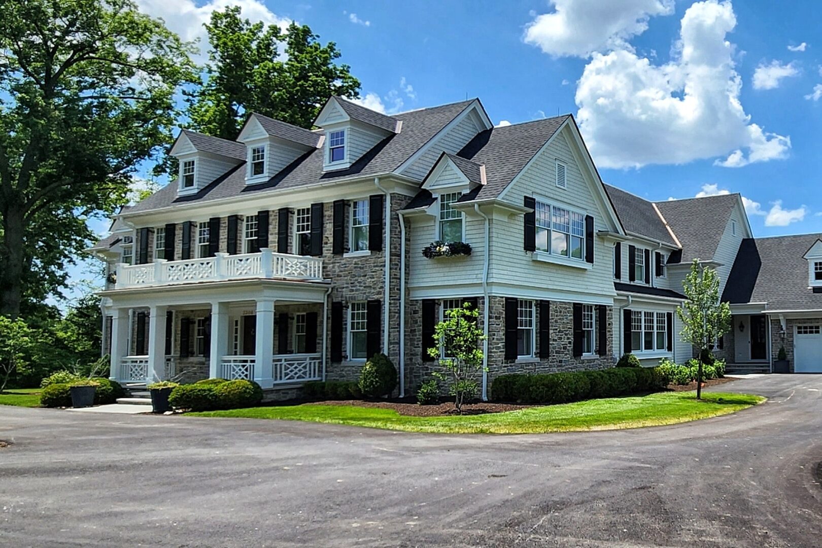 white and stone barndominium pole barn house with a long driveway and a three car white and stone pole barn garage