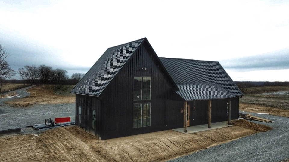a black metal 20x48 barndominium with tall windows on a cloudy day