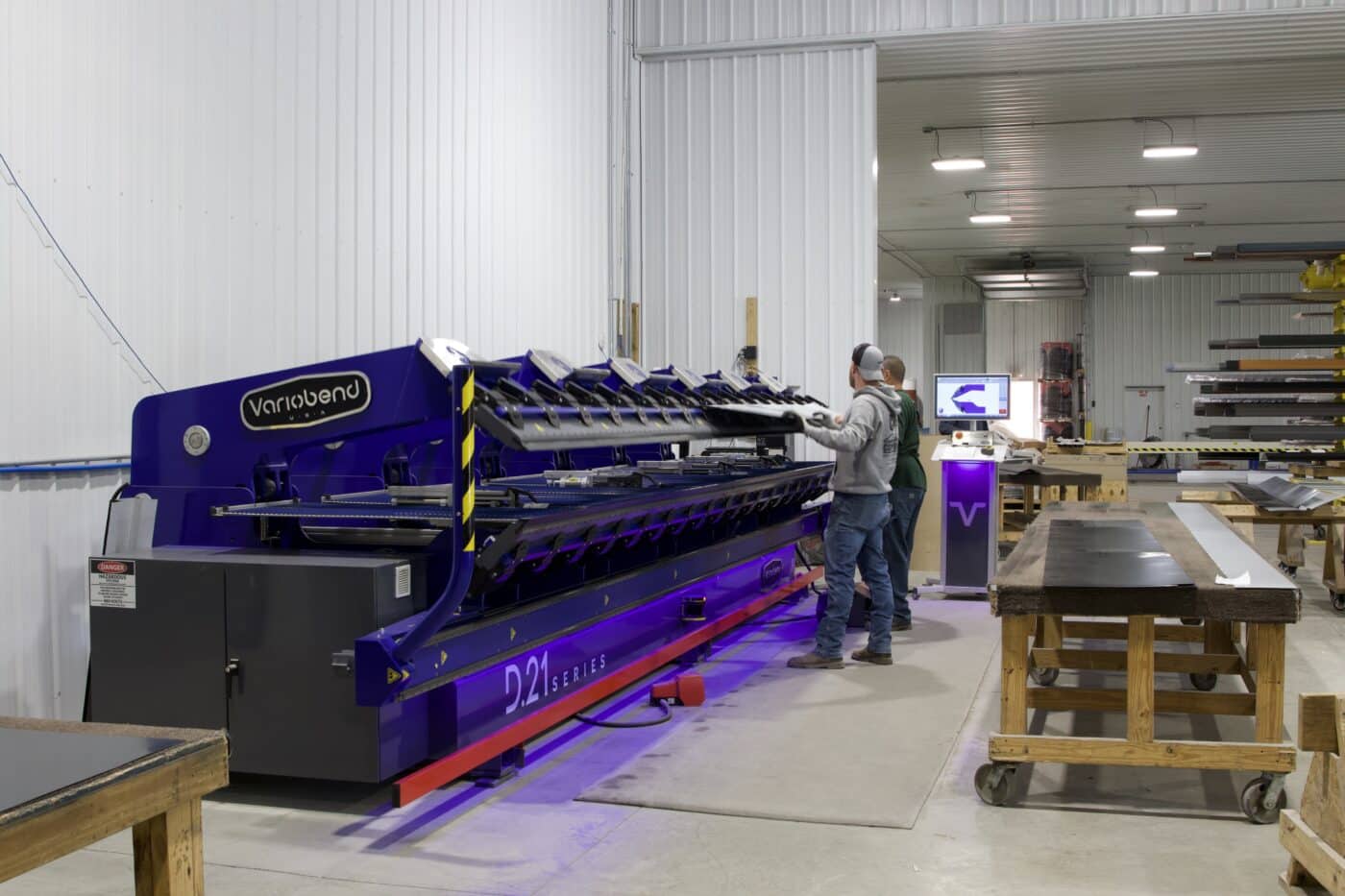 workers getting metal panels created using a blue machine