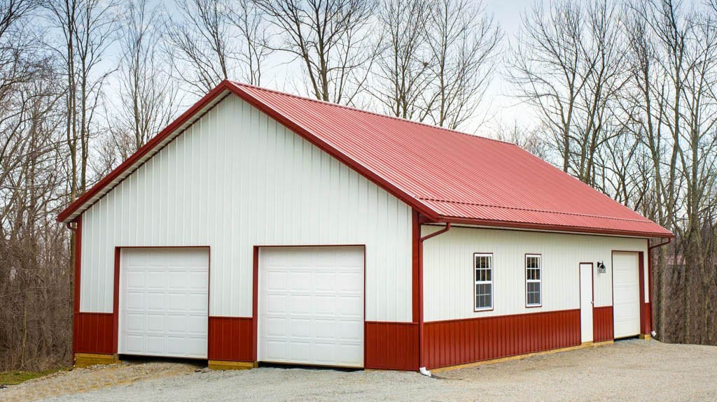 a white 20x30 pole barn garage with red trim and a red roof, with two doors
