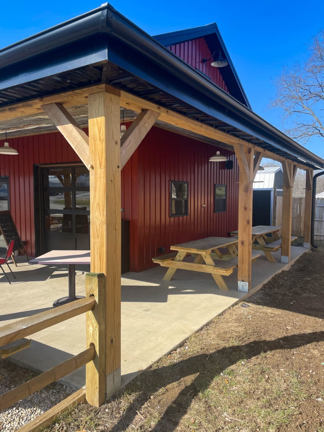 a different angle of the red metal dairy barn in leesburg OH with a porch, and tables outside for seating