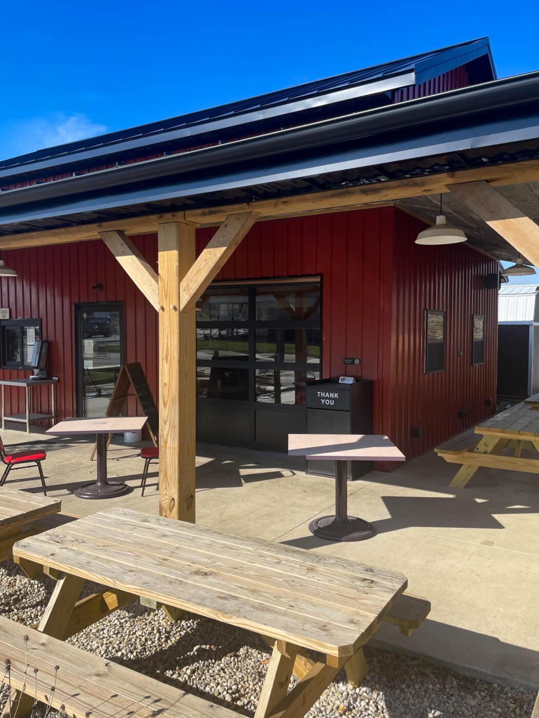 a red metal dairy barn in leesburg OH with a porch, and tables outside for seating