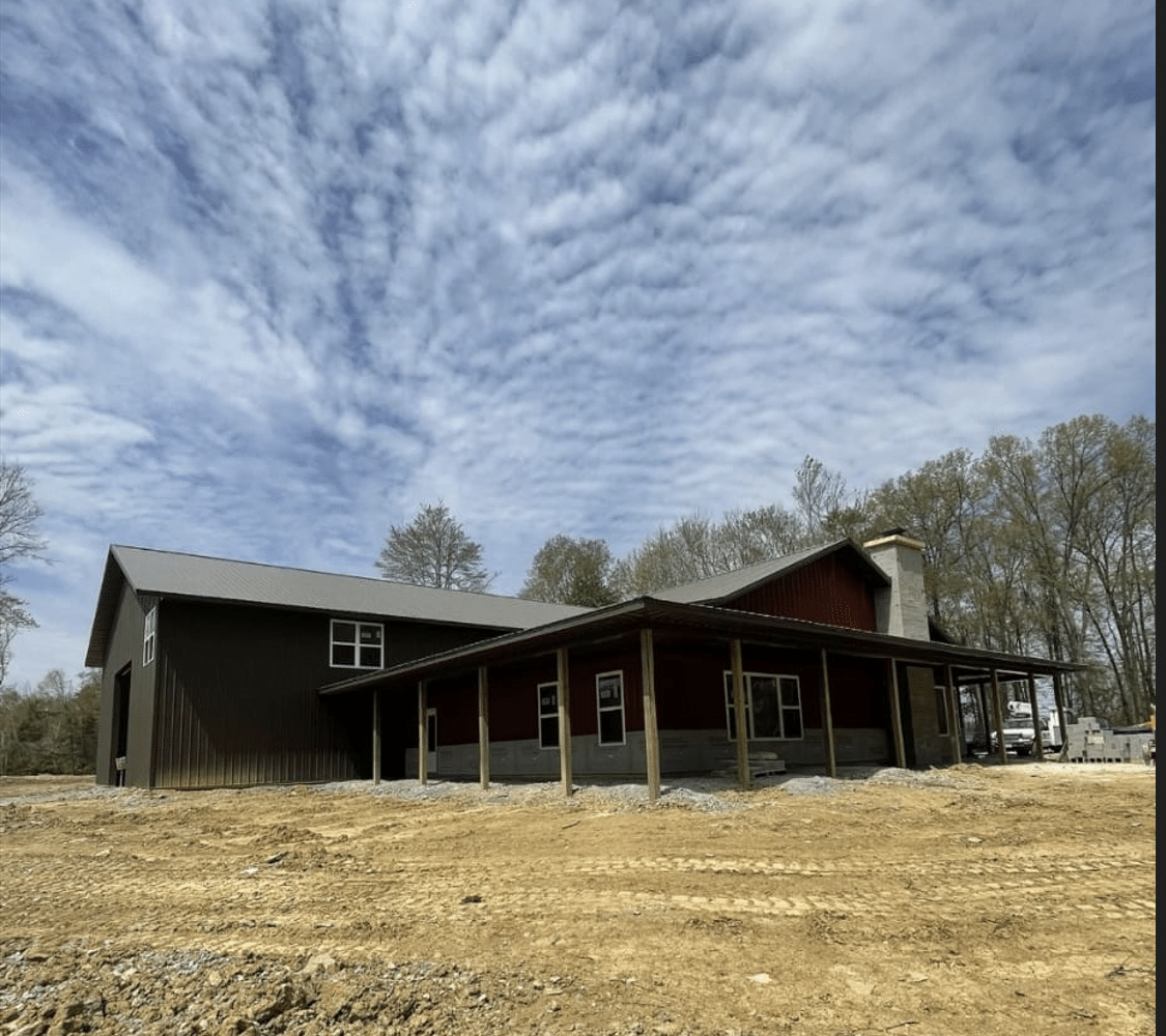 A dark 80x120 commercial pole barn in a field