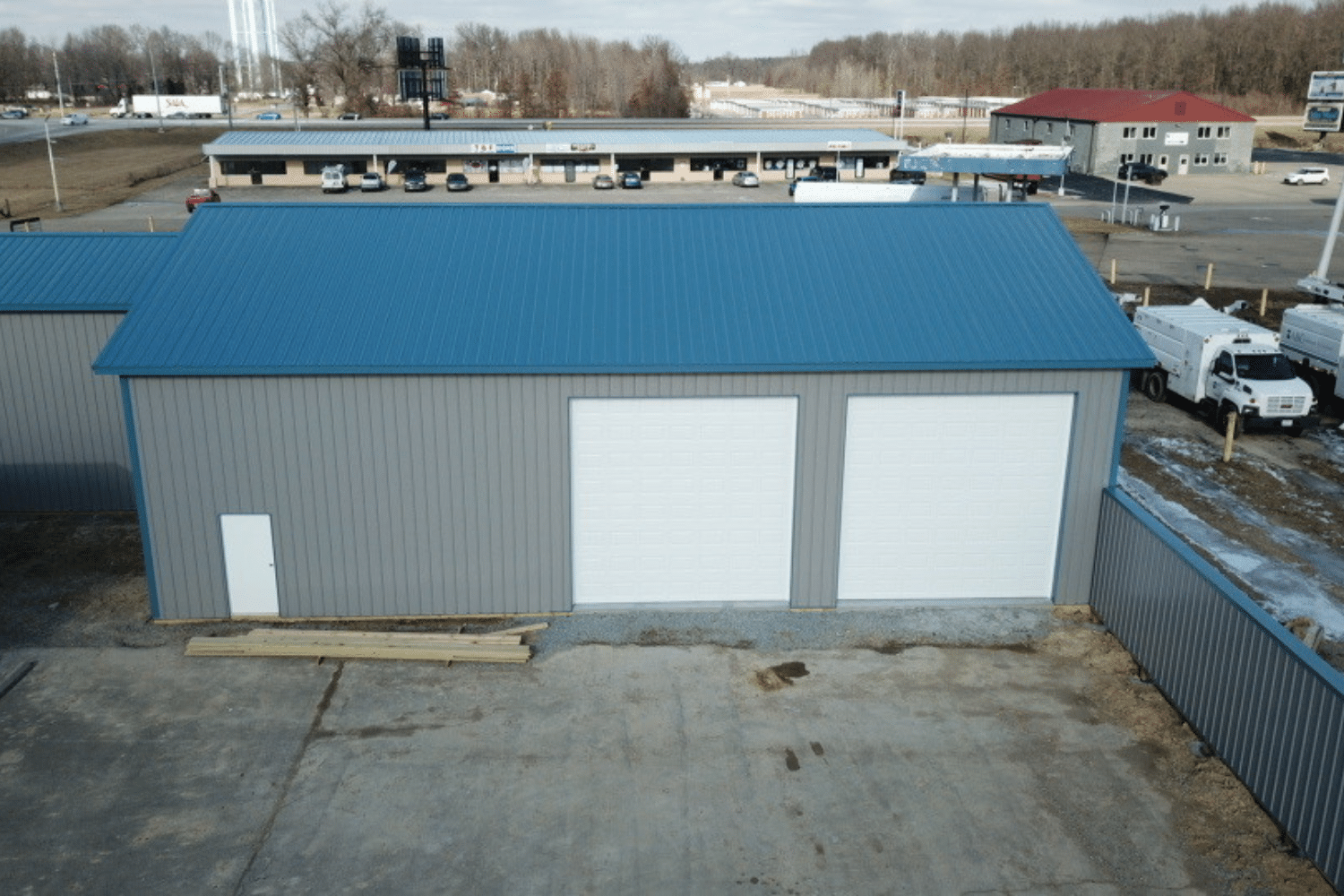 gray 40x100 garage pole barn kit with blue roof and two white garages