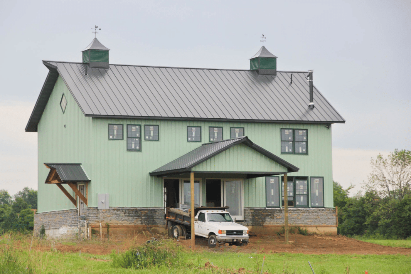 green 50x50 barndominium with truck parked in the front