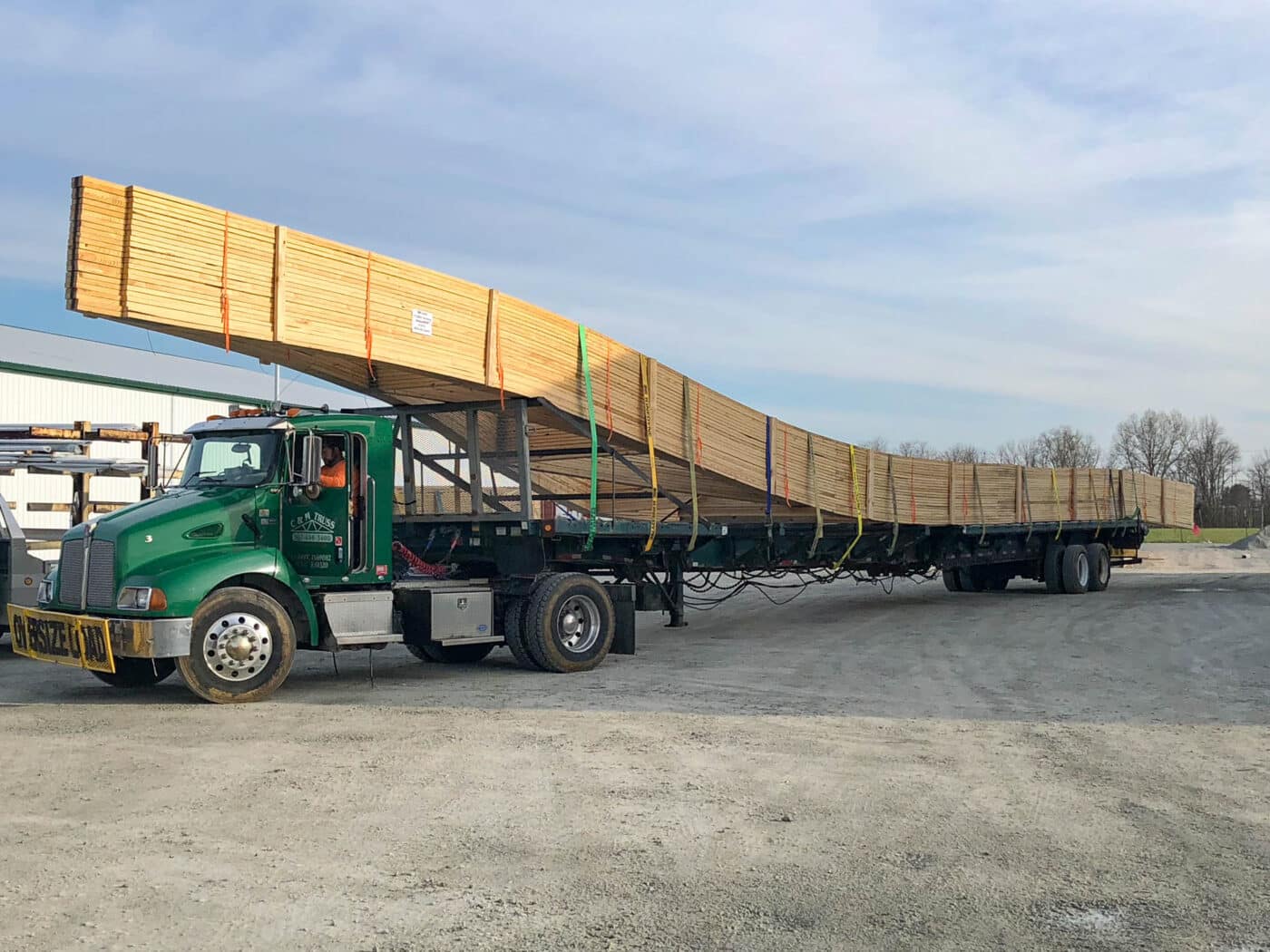 green truck with 24x24 barndominium kit supplies strapped on back leaving CMT Components manufacturing facility in Sardinia OH