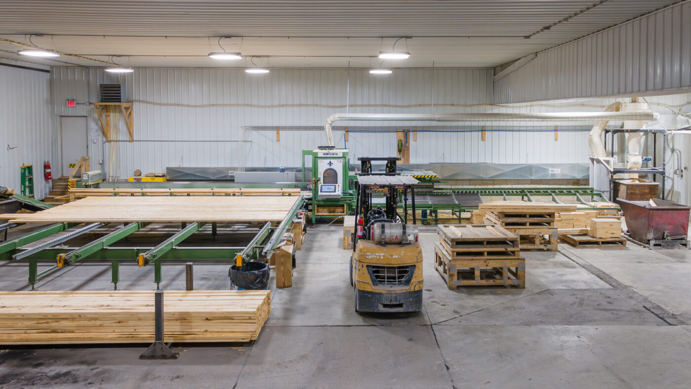 lumber stacked on green machines ready to go through and be custom cut to the specification of a 36x60 agricultural pole barn design