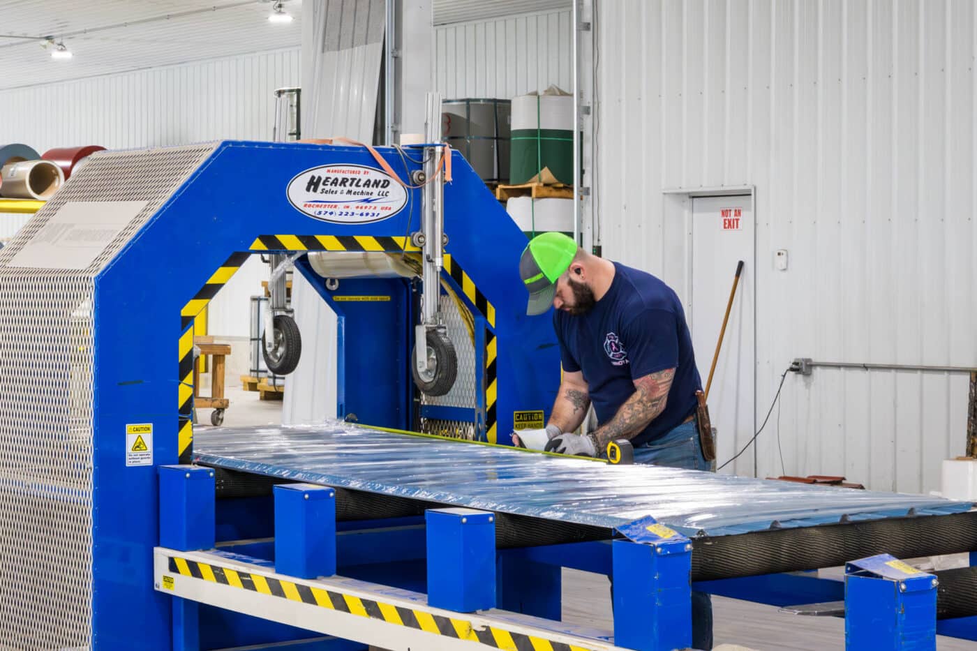 man manufacturing blue metal panels and adding a sticker on to it