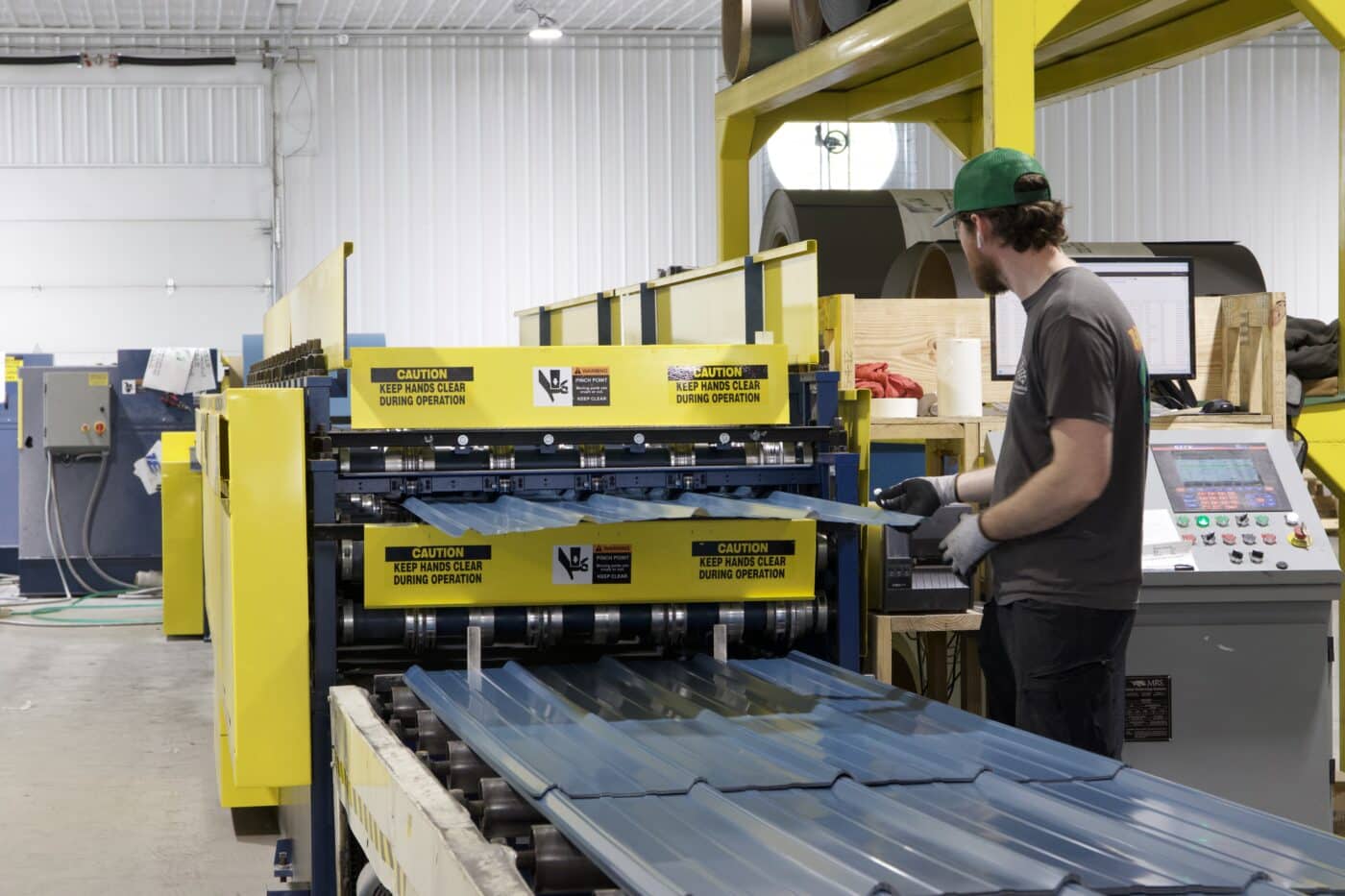 a man using a machine to manufacture metal panels for 25x50 commercial pole barns