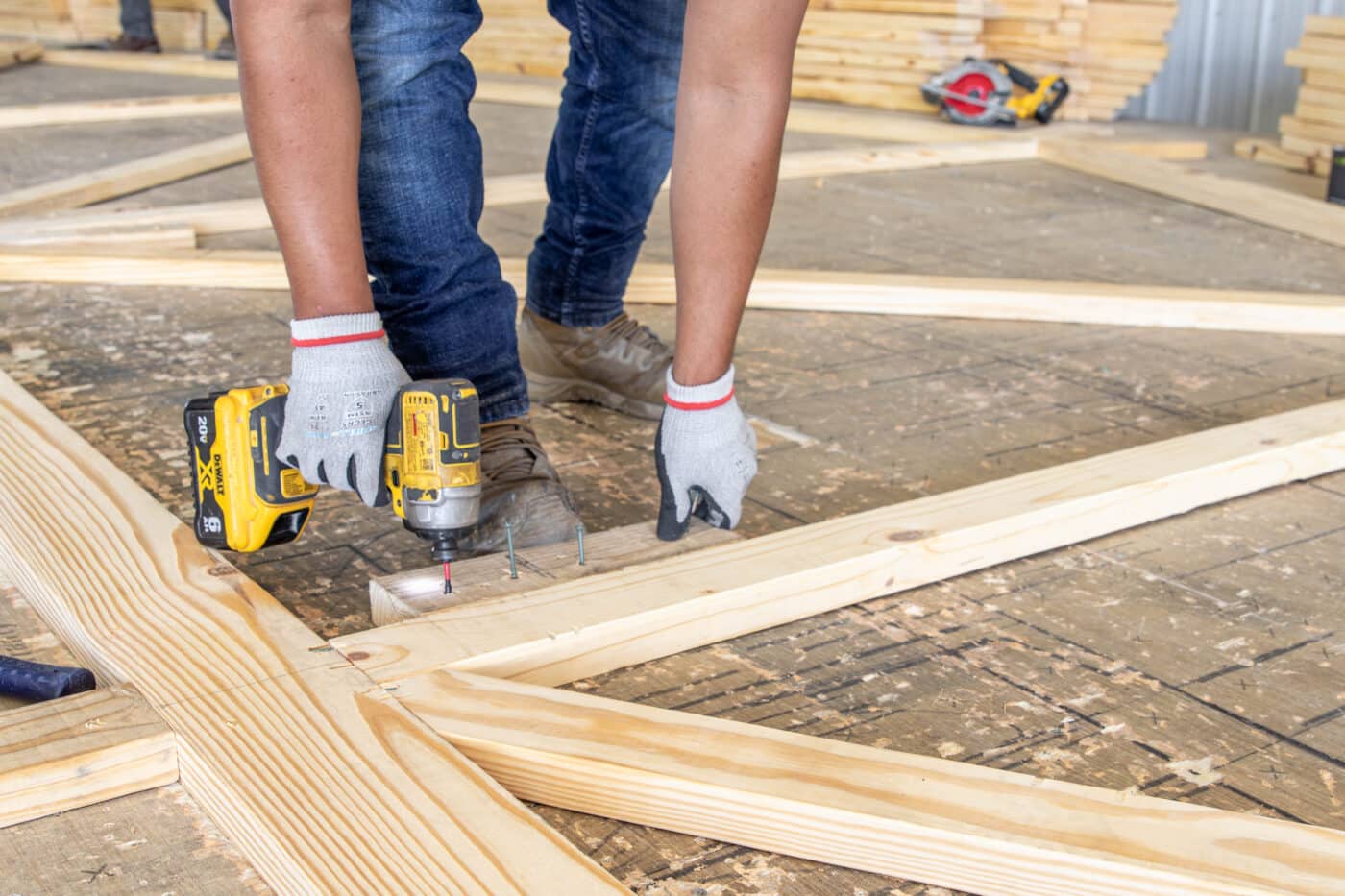 A man using a drill on roof trusses for 60x80 agricultural pole barns