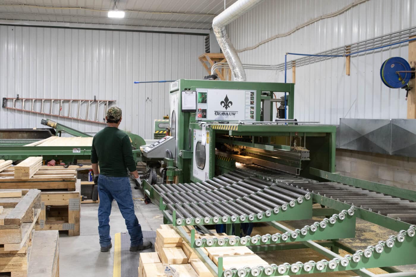 A man using a machine to cut trusses for 75x100 barndominiums