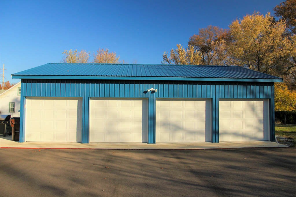 ocean blue metal siding and roofing on 36x48 pole barn garage with four white overhead doors
