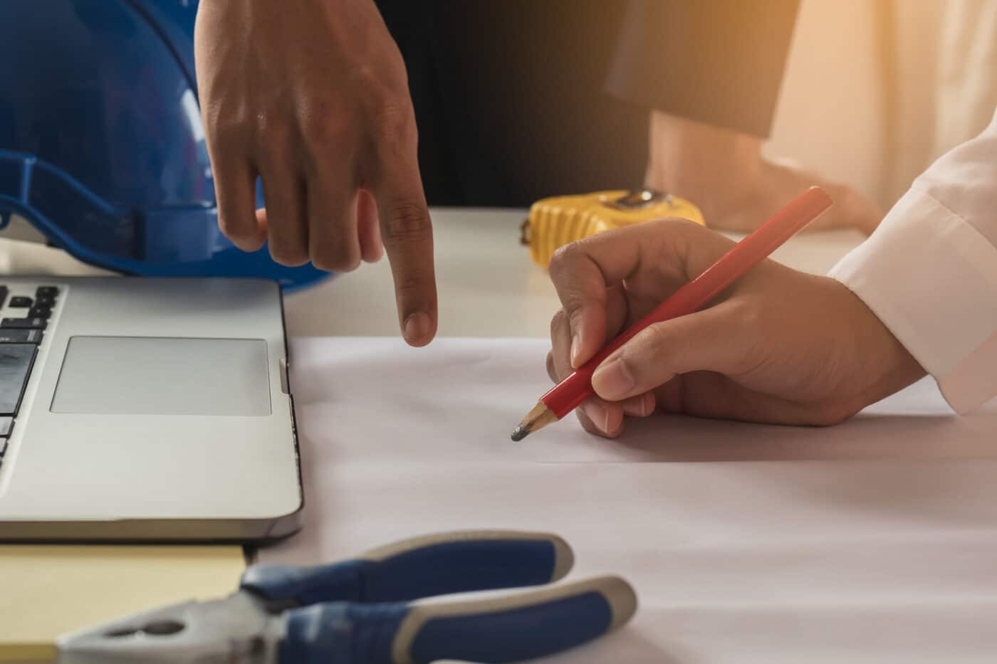 one person pointing to piece of paper while other draws the design of a 32x40 pole barn garage on paper