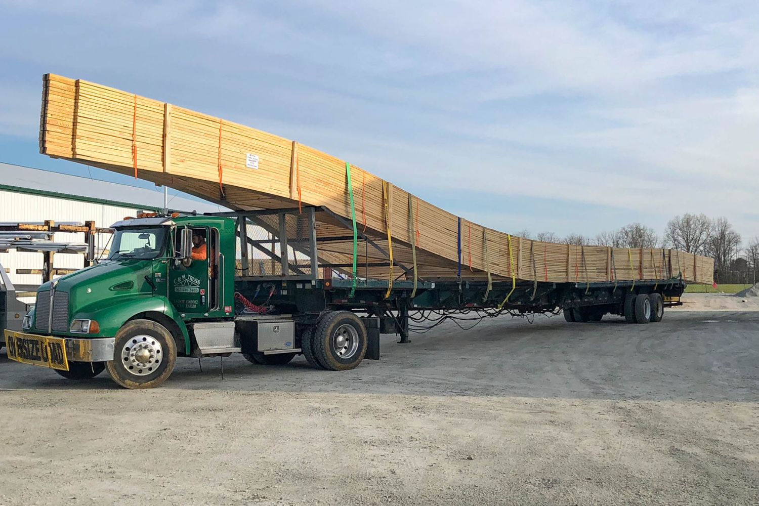 pole barn kit roof trusses strapped to the back of a green truck being delivered in Waverly OH