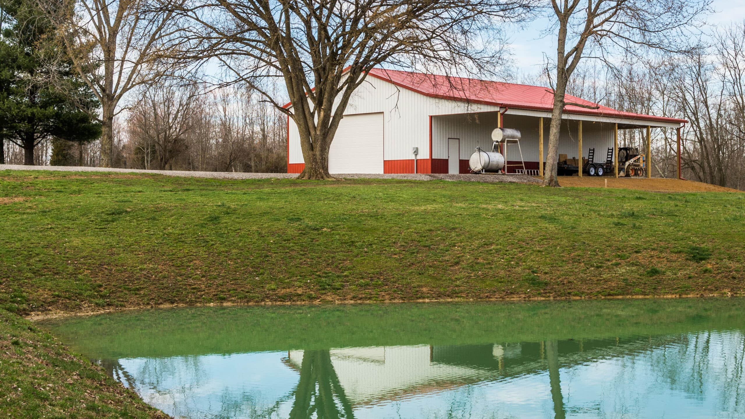 red and white livestock pole barn by body of water