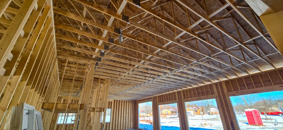 roof trusses inside home with three openings for overhead garage doors