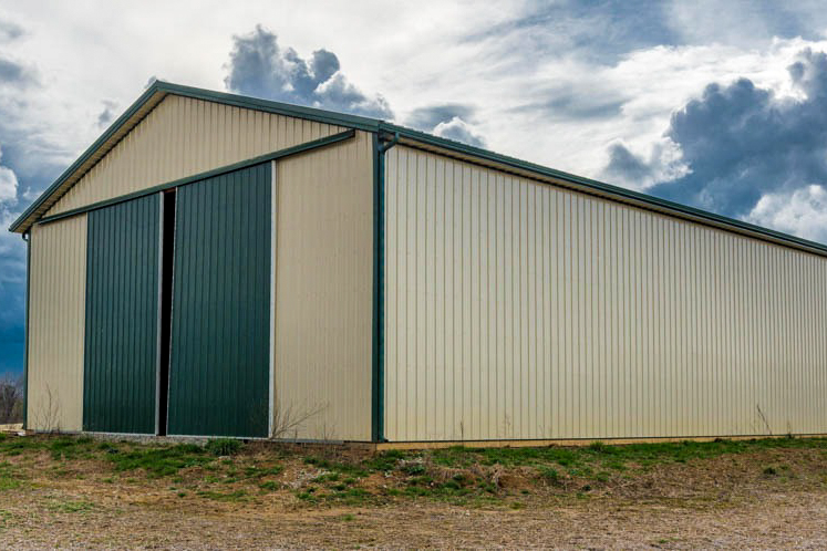 tan 40x100 pole barn with green trim and green metal slider doors