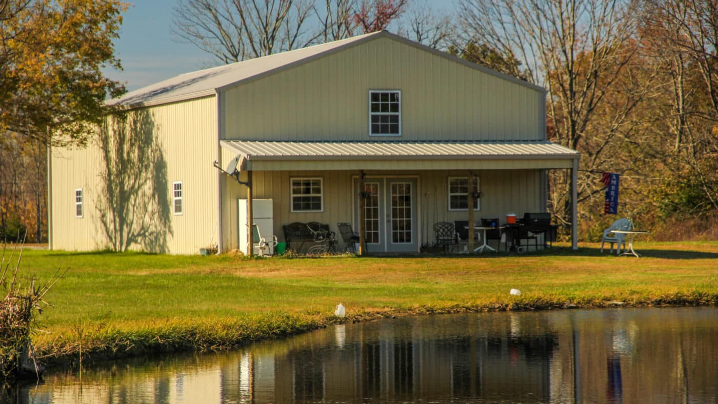 A tan barndominium standing by a lake in Cynthiana OH