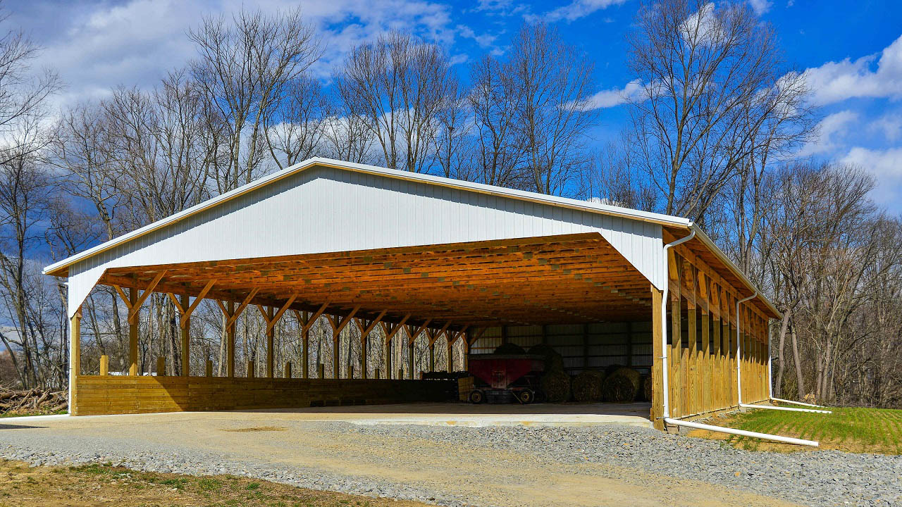 white 42x64 agricultural pole barn storing hay and farm equipment