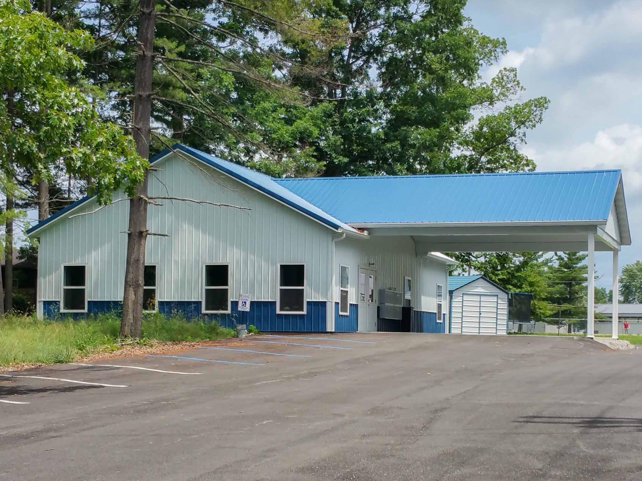 white 50x56 commercial pole barn with blue trim blue metal roof and an overhang